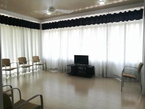 Habitación con cortinas blancas, TV y sillas. en Thilini Hotel Apartment en Ratnapura