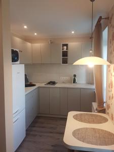 a kitchen with white cabinets and a table and a light at Boatman's harbor in Liepāja