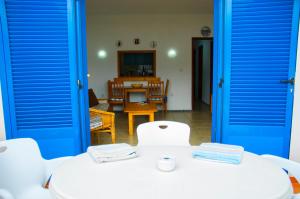 カレタ・デ・ファマラにあるSeaview Risco de Famara 2の青いドア、白いテーブルと椅子が備わる客室です。