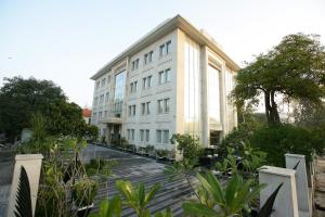 a large white building with trees in front of it at Muse Sarovar Portico Nehru Place in New Delhi