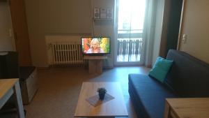 a living room with a blue couch and a tv at Landgasthof und Pension Zum löwen in Bischofsheim an der Rhön