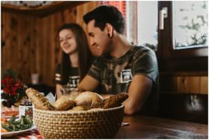 a man and a woman sitting at a table with a basket of bread at Erlebnis - Hütten Falkert by S4Y in Patergassen