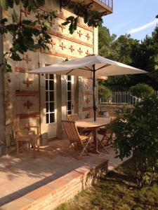 a table and chairs with an umbrella on a patio at Le Pigeonnier gîte privé climatisé avec piscine couverte et chauffée plus SPA in Alzonne