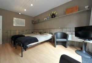 una camera con letto, sedia e televisore di aan de vaart a Mechelen