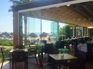 マルベーリャにあるPlaya Realのビーチを望むテーブルと椅子付きのレストラン