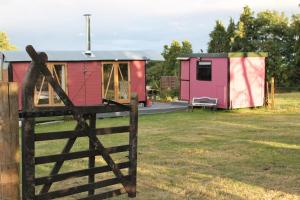 a red and pink tiny house with a fence at Off the Rails in Oswestry
