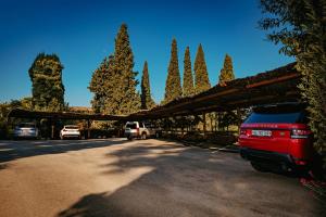 a red truck parked in a parking lot with trees at Rigat Park & Spa Hotel - Adults Recommended in Lloret de Mar