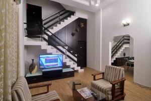 a living room with a tv and a staircase at ShreeVilla Corporate Guest House in Nashik