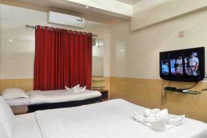 a hotel room with two beds and a tv at ShreeVilla Corporate Guest House in Nashik +11 photos