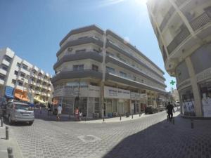 een groot gebouw in een stadsstraat met auto's bij Les Palmiers Petrou Apartments in Larnaka