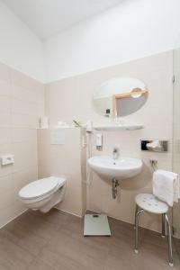 a white bathroom with a toilet and a sink at Landhotel Butjadinger Tor in Nordenham