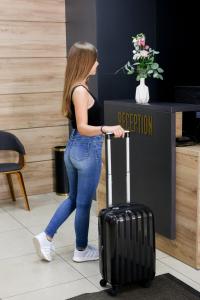 a woman pulling a suitcase in front of a reception desk at Hotel Antonio in Uzhhorod