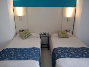 a room with two beds and a table at Hotel Nuevo Ara in Cáceres