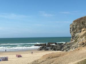 a beach with people standing on the sand and the ocean at Prince Croft Cottage in Porthtowan
