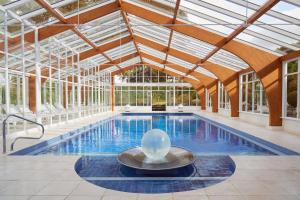 an indoor pool with a glass ceiling and a swimming pool at Summer Lodge Country House Hotel in Evershot