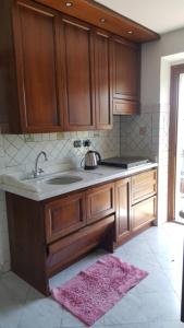 eine Küche mit Holzschränken, einer Spüle und einem Teppich in der Unterkunft Casa Gloria in Pallerone