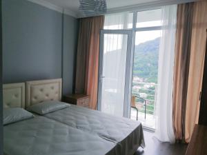 a bedroom with a bed and a large window at Albatross Kvariati Guest House in Kvariati