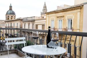 a table with two glasses of wine on a balcony at Casa Qosi B&B in Ragusa