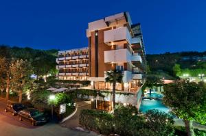 an apartment building with a swimming pool at night at Hotel Alexander in Gabicce Mare