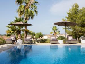 een zwembad met stoelen en parasols bij Casa Font i Roig in Maria de la Salut