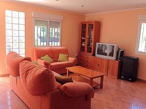 uma sala de estar com um sofá e uma televisão em Chalet en el Monte con Piscina em Sagunto