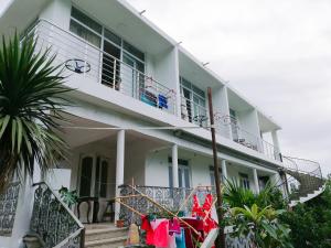 a white building with a balcony and a palm tree at Albatross Kvariati Guest House in Kvariati