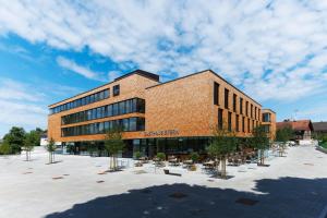 a large brick building with trees in a courtyard at Sternen Hotel Wolfurt in Bregenz