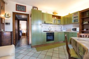 una cocina con armarios verdes y una mesa en La Sartia Apartment, en Porto Pozzo