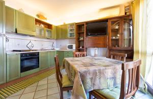 una cocina con armarios verdes y una mesa con sillas en La Sartia Apartment, en Porto Pozzo