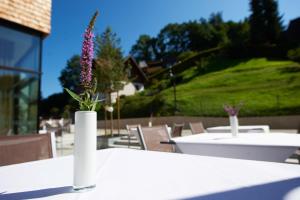 a white vase with a purple flower on a table at Sternen Hotel Wolfurt in Bregenz