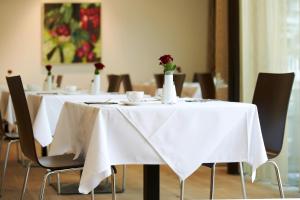 a table with white table cloth and vases with flowers on it at Sternen Hotel Wolfurt in Bregenz