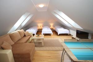 a attic room with a couch and two beds at Apartamenty Olsztyn in Olsztyn