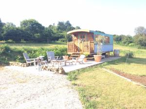 a rv with a deck and chairs and a table at Roulotte de luxe vue mer 180° ,et un ha de verdure in Plougastel-Daoulas