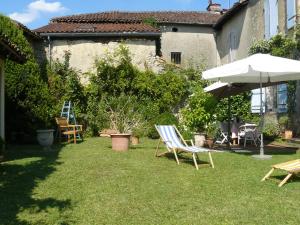 un patio con sillas, sombrilla y sombrilla en Le Presbytère en Labastide-dʼArmagnac