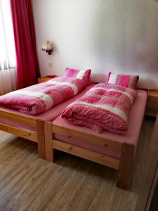 two beds in a bedroom with pink sheets and pillows at Apartmenthaus Sunshine in Saas-Grund