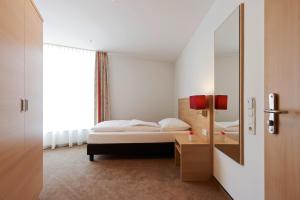 a bedroom with a bed and a large mirror at Sternen Hotel Wolfurt in Bregenz