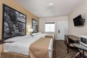 a hotel room with two beds and a flat screen tv at Super 8 by Wyndham Watrous in Watrous