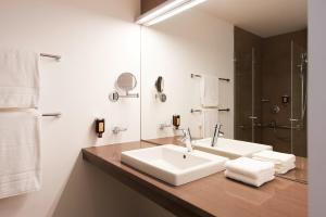 a white bathroom with a sink and a shower at Sternen Hotel Wolfurt in Bregenz