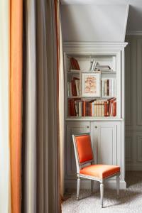 a room with a book shelf and a chair at Hôtel Plaza Athénée - Dorchester Collection in Paris
