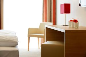 a bedroom with a desk and a chair and a bed at Sternen Hotel Wolfurt in Bregenz
