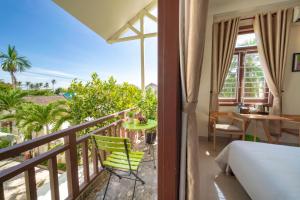 a bedroom with a balcony with a bed and a desk at Green Garden Hoi An Homestay in Hoi An