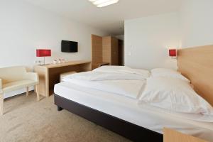a bedroom with a large white bed and a desk at Sternen Hotel Wolfurt in Bregenz