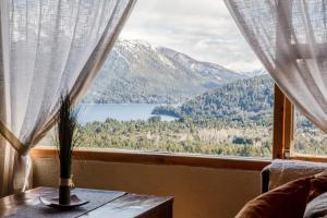 a window with a view of a lake and mountains at Estancia Del Carmen Mountain Resort in San Carlos de Bariloche