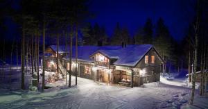 a log cabin in the snow at night at Isokenkäisten Klubi - Wilderness Lodge in Kiviperä