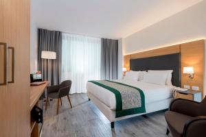 a hotel room with a large bed and a desk at Holiday Inn Naples by IHG in Naples +98 photos