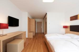 a bedroom with a bed and a desk with a television at Sternen Hotel Wolfurt in Bregenz