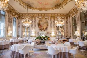 a dining room with white tables and chandeliers at Le Meurice – Dorchester Collection in Paris