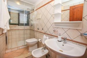 ein Badezimmer mit Waschbecken, Toilette und Spiegel in der Unterkunft La Terrazza di Viola in Scicli