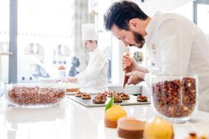 a chef preparing food in a kitchen at Le Meurice – Dorchester Collection in Paris