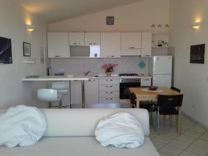 Appartamento Elegante E Panoramico Con Splendida Vista Mare في بوجيرو: مطبخ مع أريكة وطاولة ومطبخ مع دواليب بيضاء